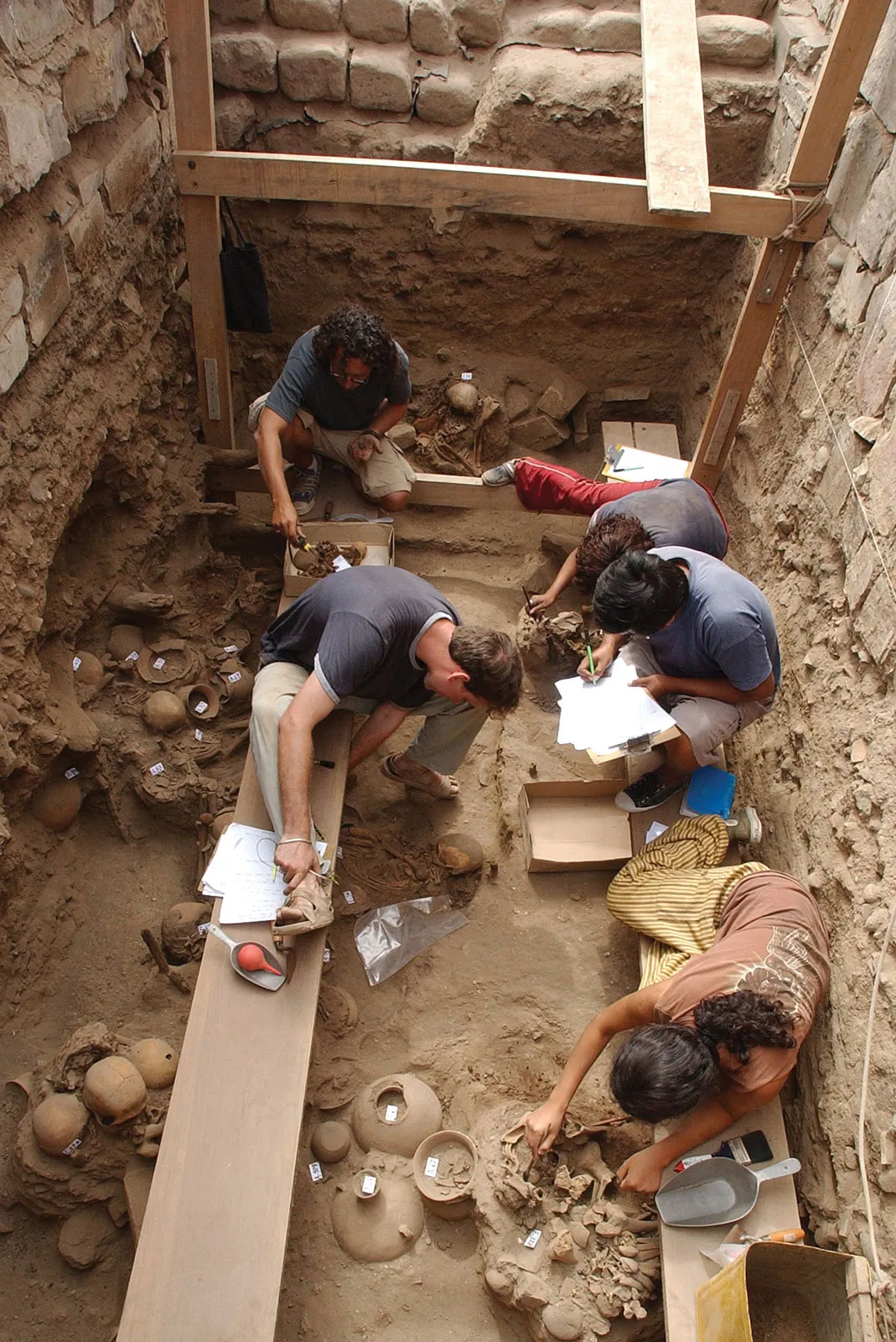 Archaeologists documenting artifacts at a dig site. Archaeologists documenting their artifacts in a dig site.